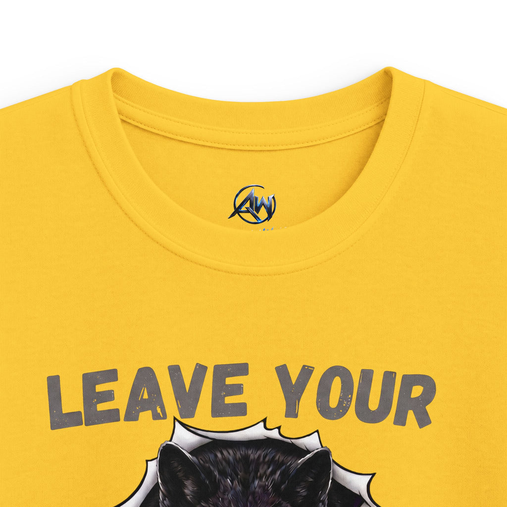 Close-up of a yellow t-shirt featuring the text 'LEAVE YOUR' in gray above a graphic of a black cat's head popping out of a white burst. A small circular logo with 'AW' is printed inside the collar.
