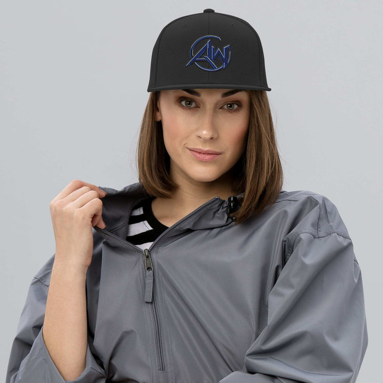 Woman wearing a black cap with AW logo and a gray raincoat on a light gray background