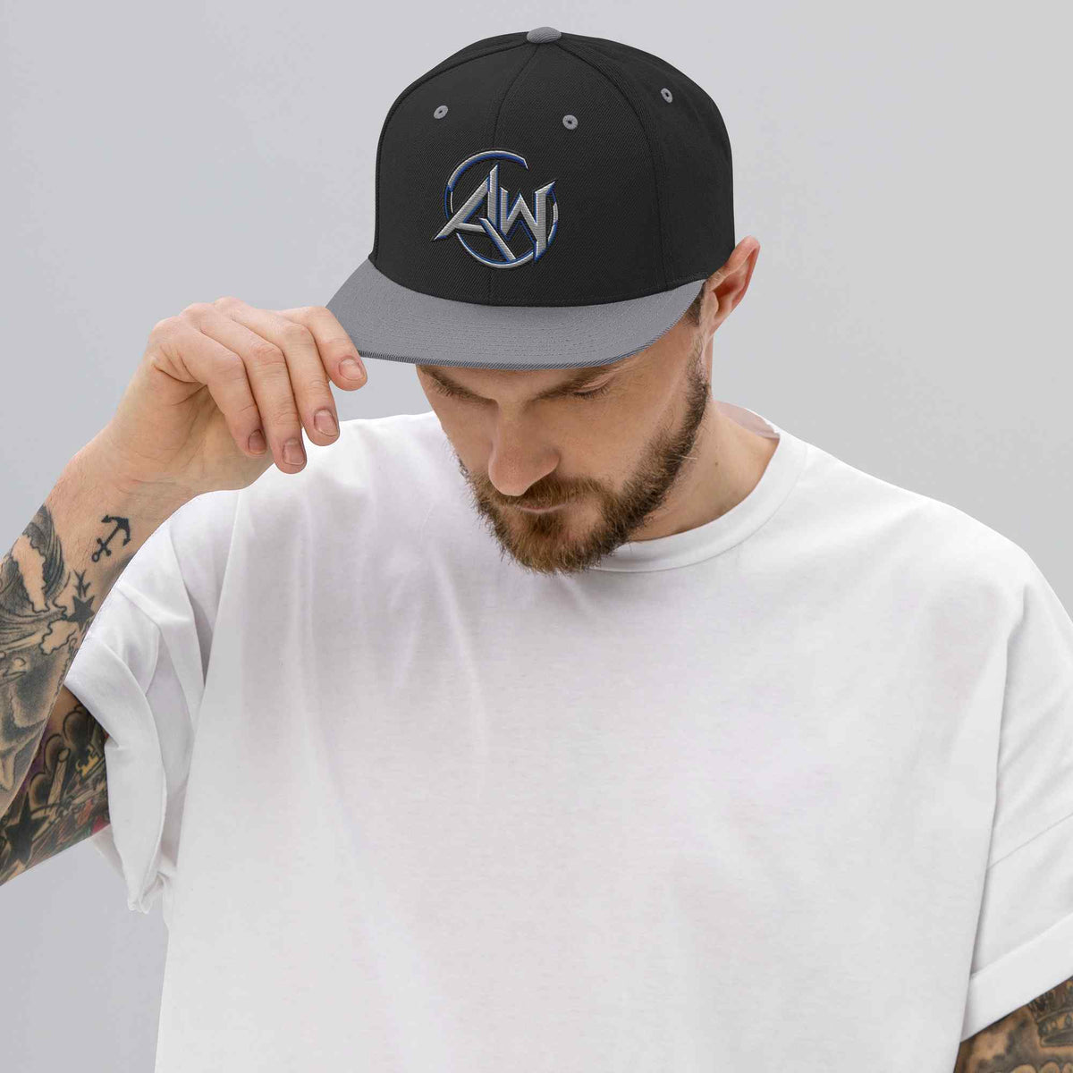 Man wearing a black and silver cap with text, AW logo on a plain background
