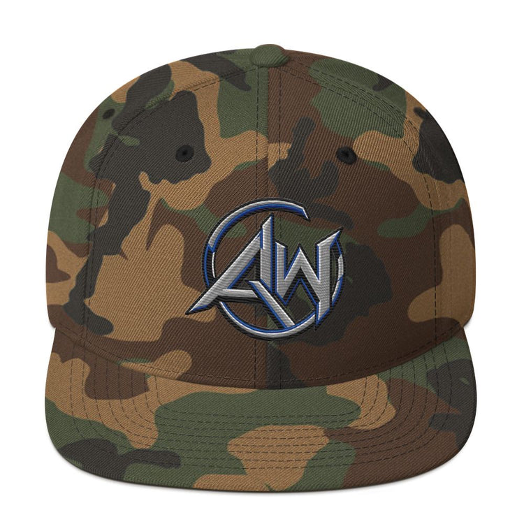 A structured camouflage baseball cap with a flat brim, featuring a central metallic silver and blue embroidered logo that reads 'AW' inside a circular design. The cap has a woodland camo pattern in shades of brown, green, and tan, presented on a clean white background.