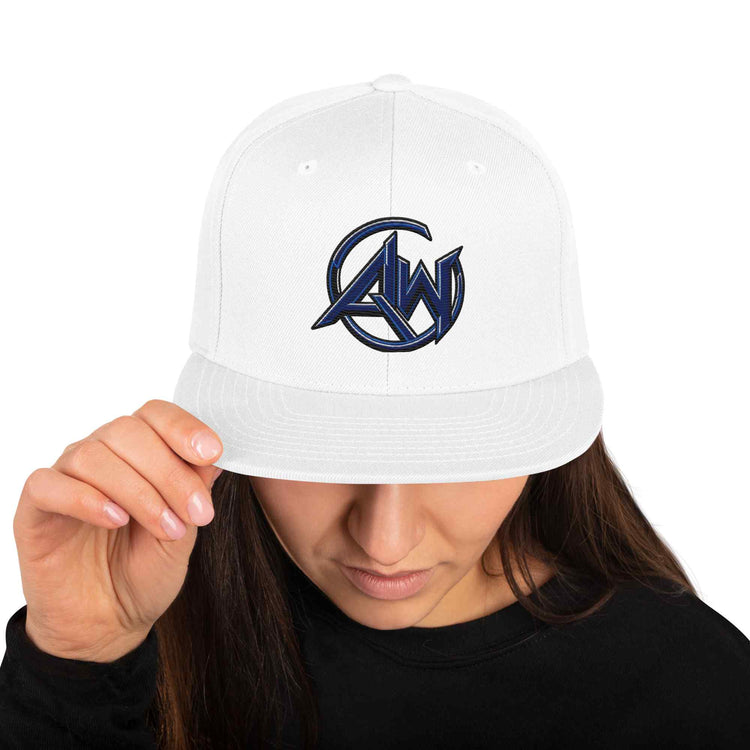 A white snapback cap with a navy blue and black embroidered 'AW' logo on the front, worn by a model who is holding the brim with one hand.