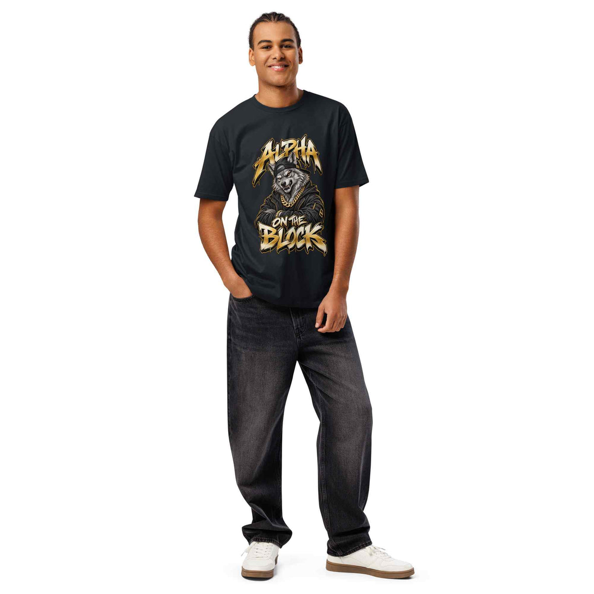 A man modeling a black graphic t-shirt with a gold and white 'Alpha on the Block'  wolf design, paired with dark gray jeans and white sneakers, against a plain white background.