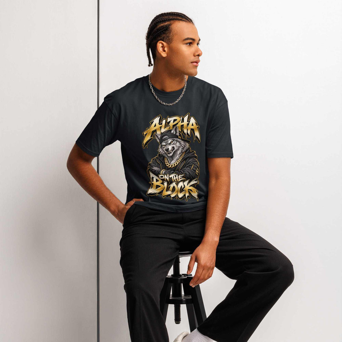 man wearing a black t-shirt with wolf design, man sitting on a stool against a light gray background.