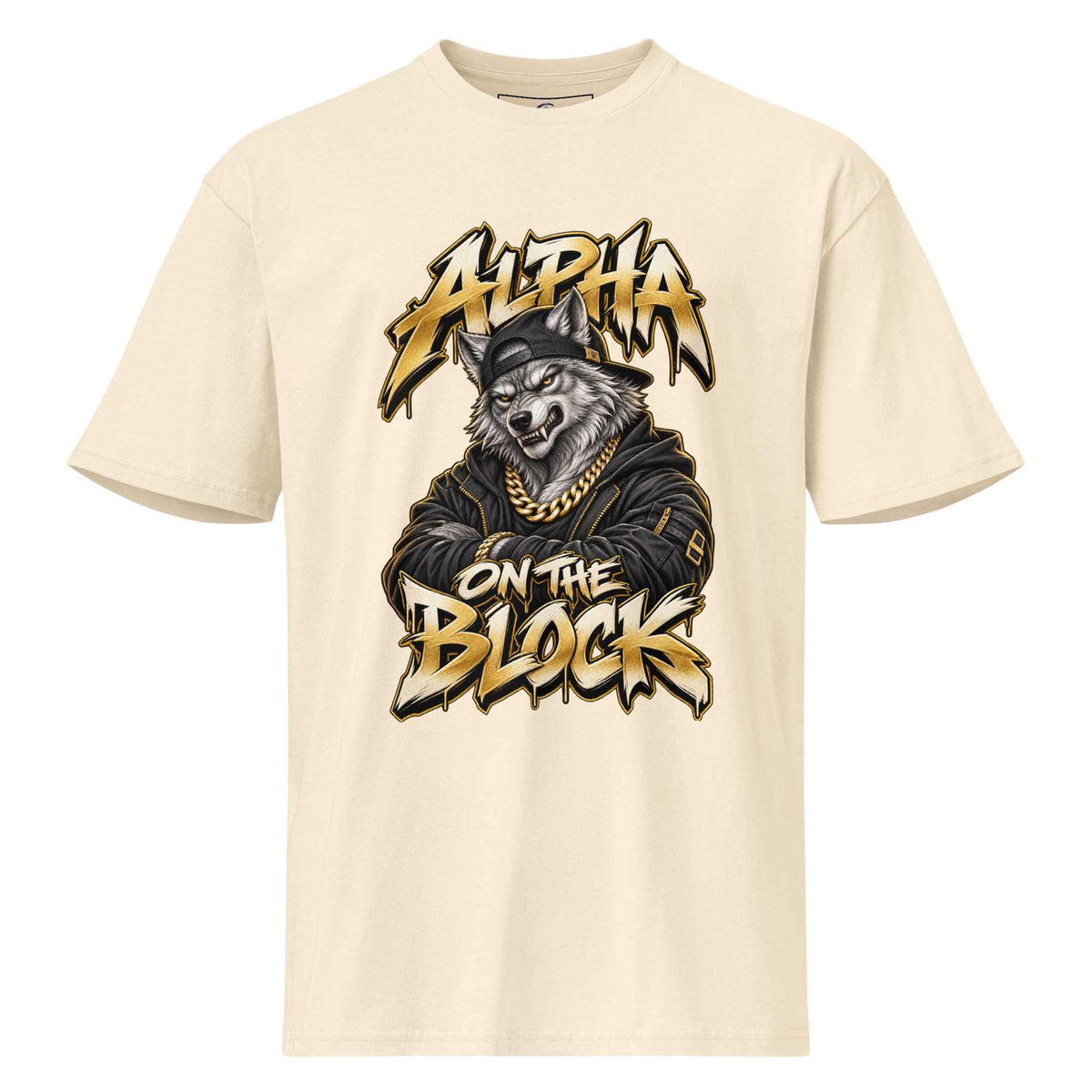 A cream-colored short-sleeve t-shirt with a large graphic print on the front. The graphic features a wolf wearing a black cap and gold chain, with stylized text reading 'ALPHA ON THE BLOCK' in a gold and black graffiti font.