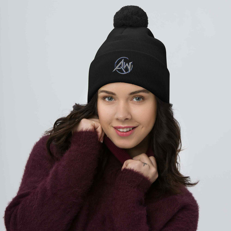 Woman wearing a black beanie pom pom  with 'AW' logo on a gray background
