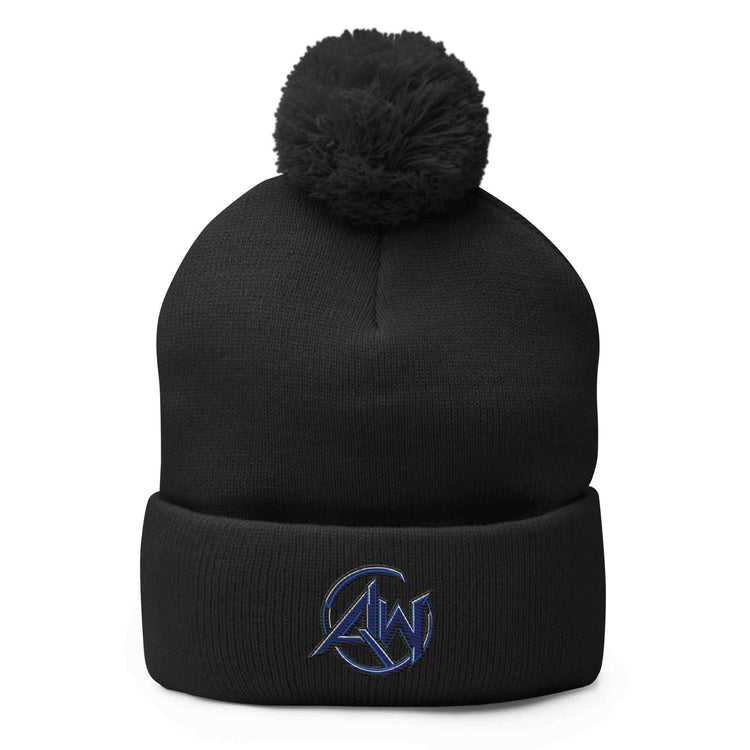 A black knit pom-pom beanie with a folded cuff, featuring a circular blue AW' logo patch on the front cuff, set against a plain white background.