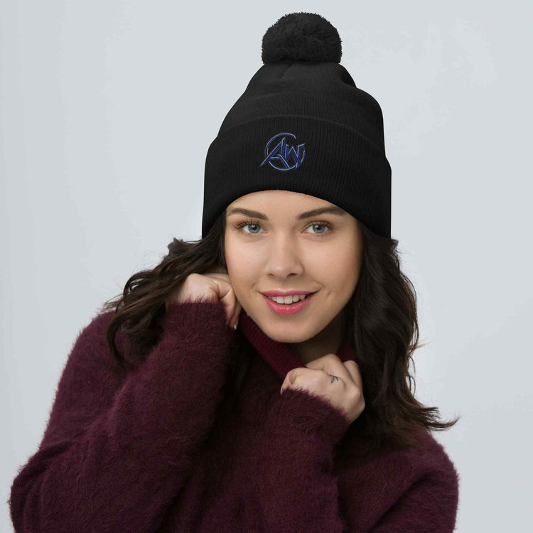 Woman wearing a navy blue beanie with a pom-pom on a light gray background