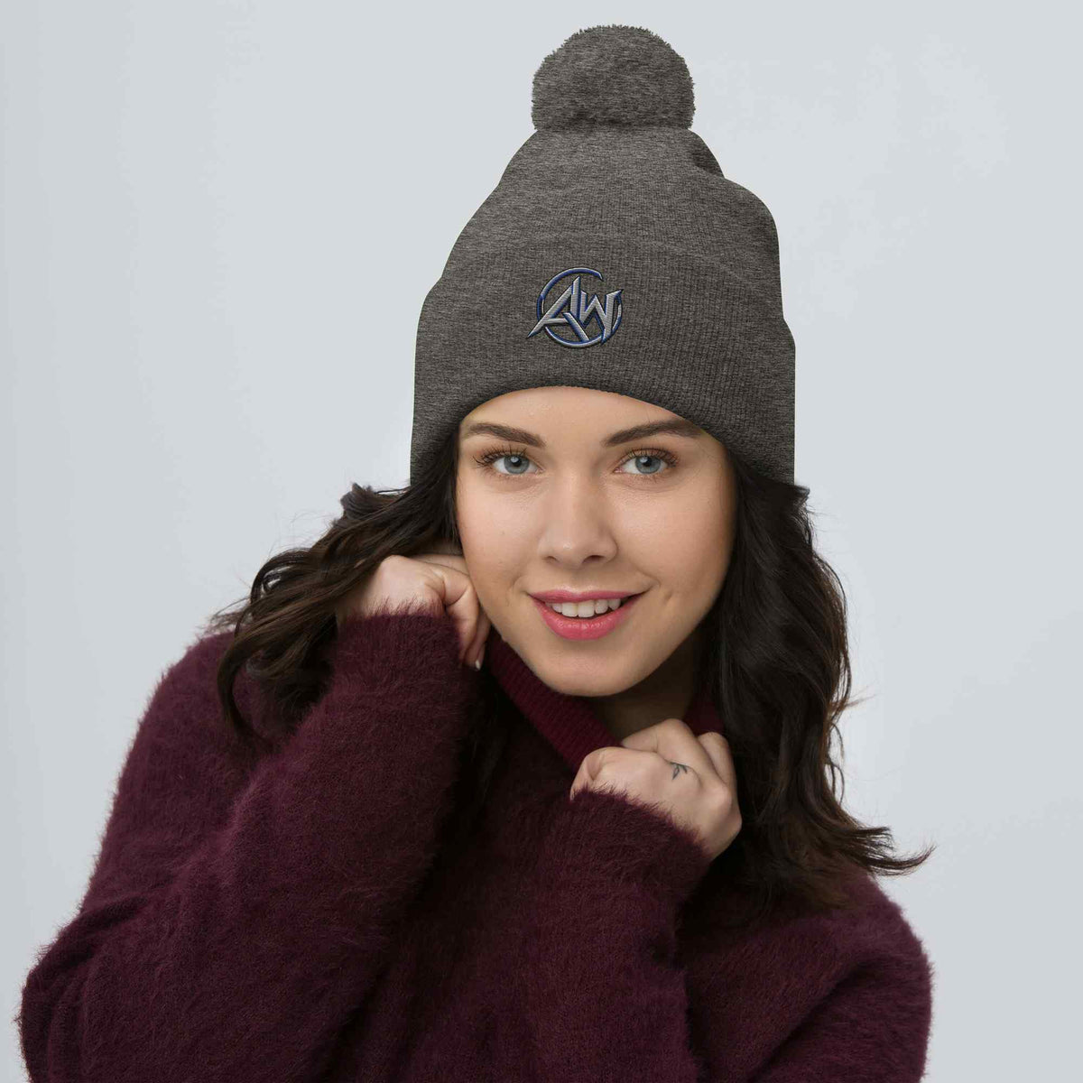 Woman wearing a gray beanie with a pom-pom on a light gray  background