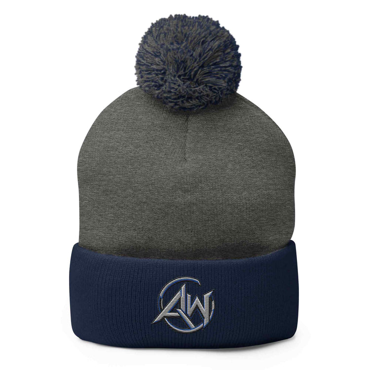A dark gray knit beanie with a navy blue pom-pom and a matching navy blue folded cuff. The cuff features a small white embroidered AW logo