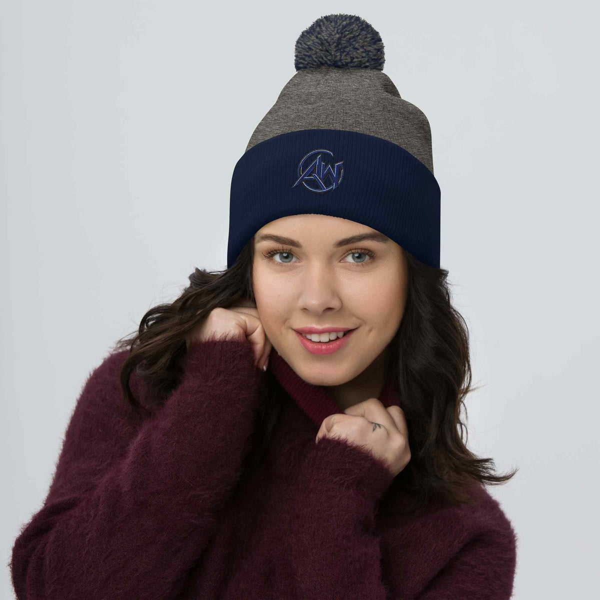 Woman wearing a two-tone beanie with a logo on a plain background