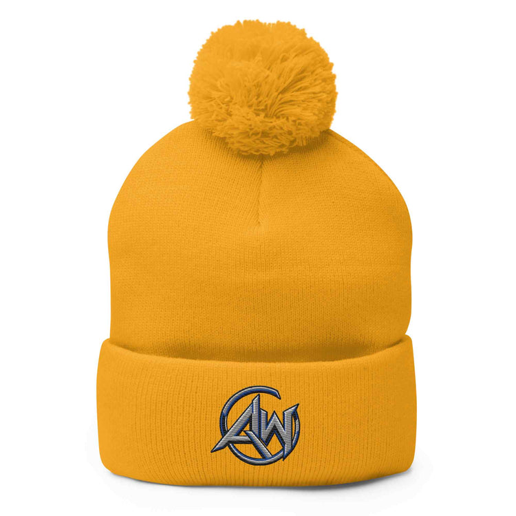 A mustard yellow knit pom-pom beanie with a folded cuff and a gray and black embroidered 'AW' logo on the front, shown against a plain white background.