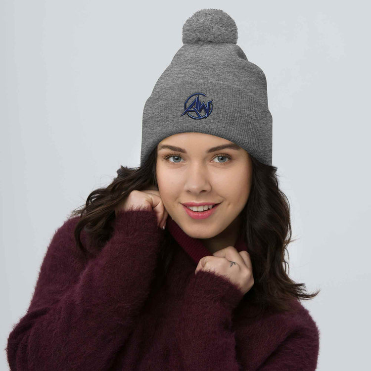 Woman wearing a gray knit beanie with a pom-pom on a light gray background