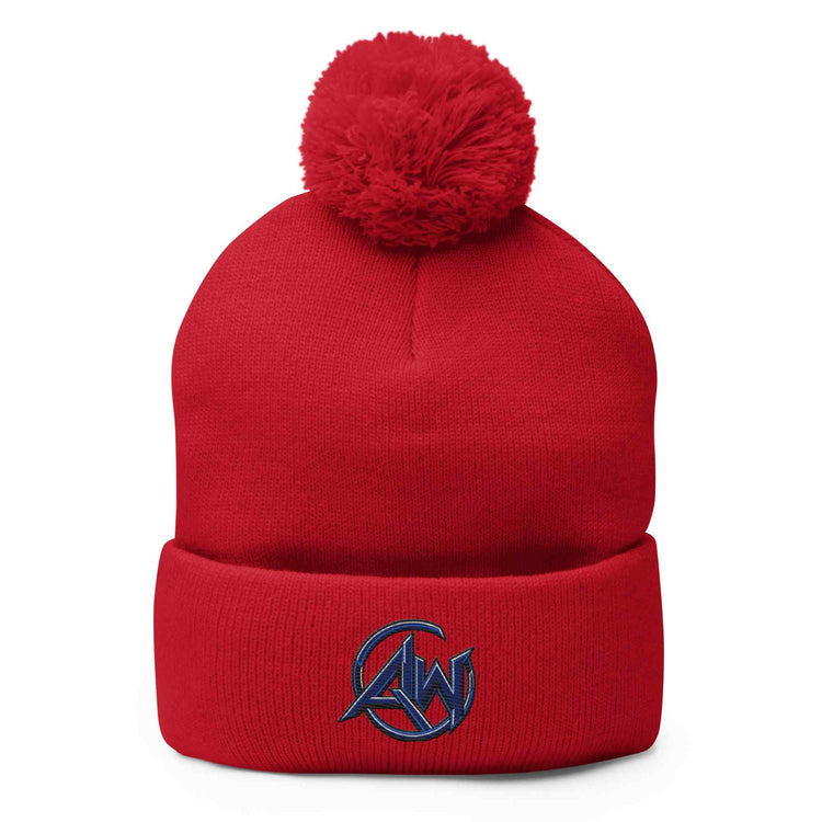 A red knit pom-pom beanie with a folded cuff and a navy blue embroidered  circular AW logo on the front, shown against a plain white background.