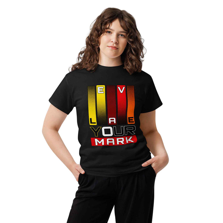 A woman modeling a black short-sleeve t-shirt with a colorful graphic that reads 'LEAVE YOUR MARK' in yellow, red, and white block letters, paired with black pants against a plain white background.
