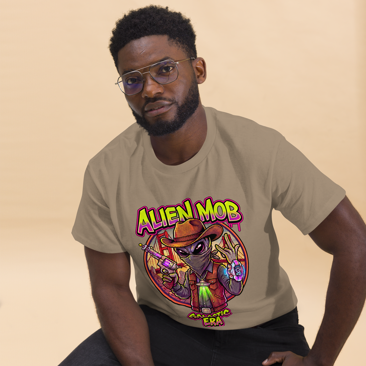 A man wearing a beige graphic t-shirt with a colorful cartoon alien design and the text 'ALIEN MOB' GALACTIC ERA