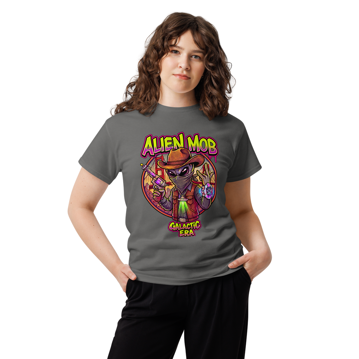 A woman modeling a dark gray t-shirt with a colorful graphic of an alien wearing a cowboy hat and vest, with the text 'ALIEN MOB' and 'GALACTIC ERA'.