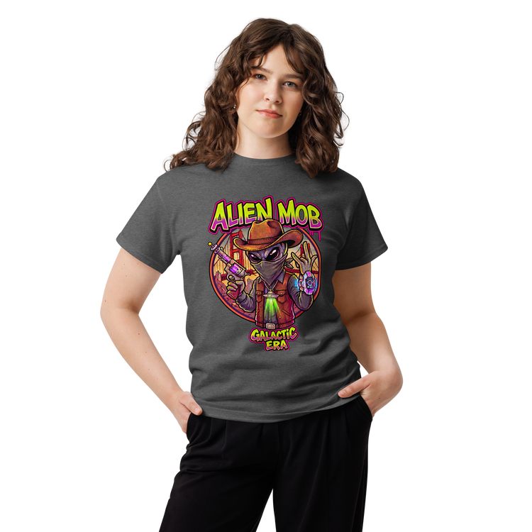 A young woman with wavy brown hair wearing a dark gray graphic  Alien mob galactic ERA' t-shirt and black sweatpants, standing against a plain white background.