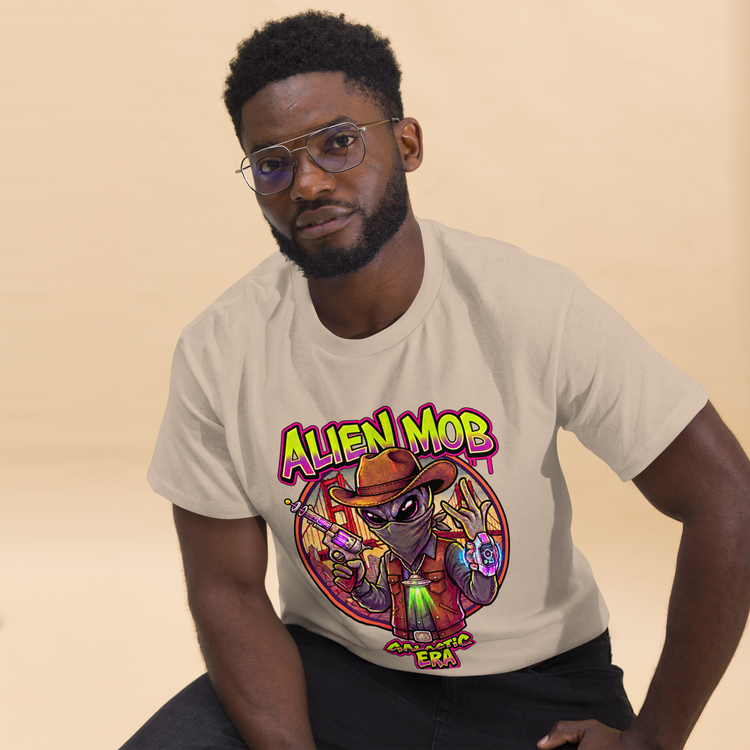 A man wearing a light beige graphic t-shirt with a colorful cartoon alien design and the text 'ALIEN MOB' GALACTIC ERA