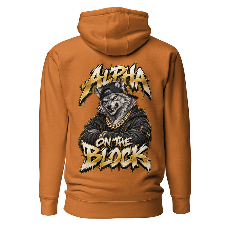 A burnt orange pullover hoodie shown from the back, featuring a large graphic print of a wolf wearing a black cap and gold chain, with the text 'ALPHA ON THE BLOCK' in a stylized gold and black font.