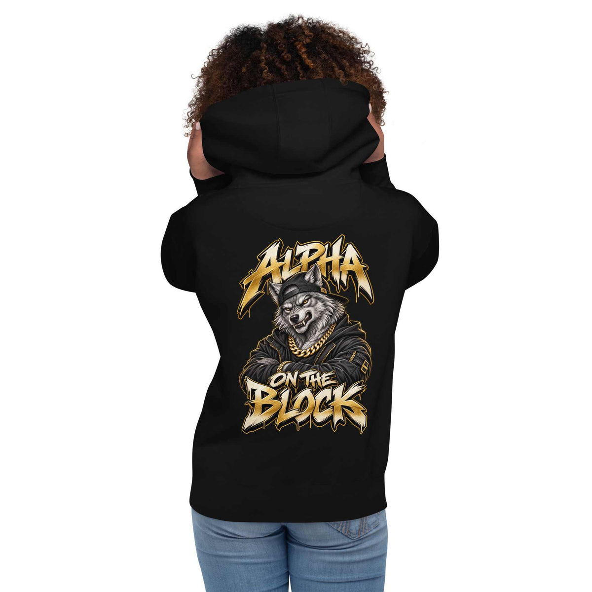 A woman shown from the back wearing a black hoodie with a large graphic print on the back. The graphic features a wolf wearing a cap and gold chain with the text 'ALPHA ON THE BLOCK' in a stylized gold and white font.