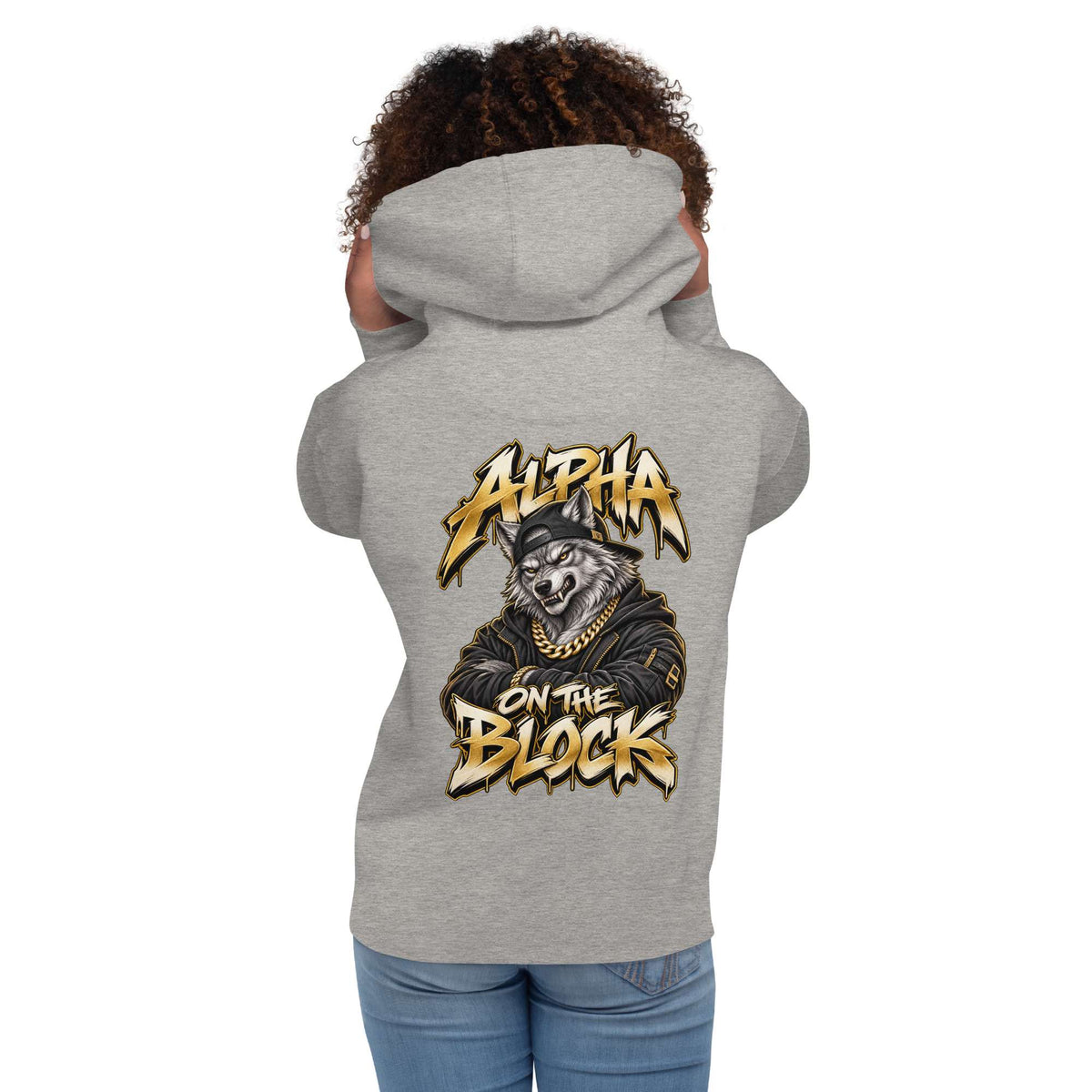 A woman model shown from the back wearing a heather gray hoodie with a large graphic print on the back. The graphic features a wolf wearing a cap and gold chain with the text 'ALPHA ON THE BLOCK' in a stylized yellow and black font.