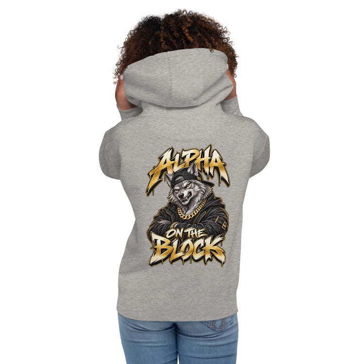A woman model shown from the back wearing a heather gray hoodie with a large graphic print on the back. The graphic features a wolf wearing a cap and gold chain with the text 'ALPHA ON THE BLOCK' in a stylized yellow and black font.