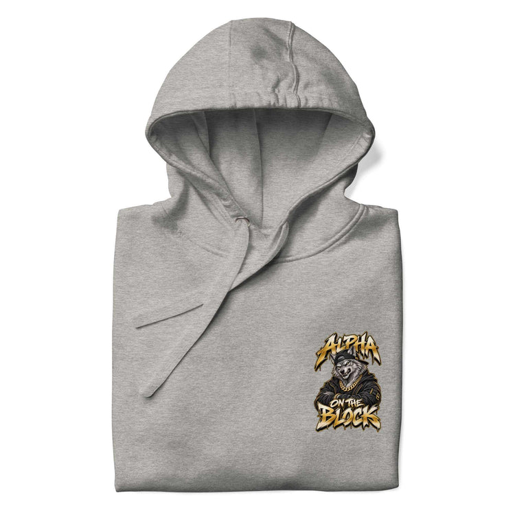 A folded heather gray hoodie with a small chest graphic on the wearer's left side. The graphic features the text 'ALPHA ON THE BLOCK' in a stylized yellow and black font above an illustration of a wolf wearing a black hood.