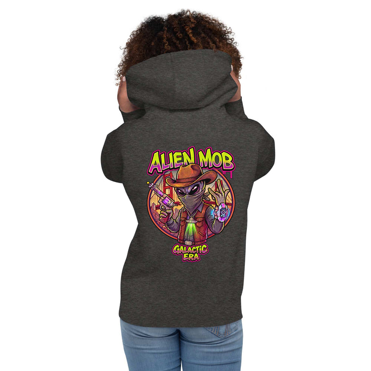 woman wearing a charcoal hoodie with alien mob cowboy outlaw  on the back of the hoodie paired with blue jeans on a white background back view