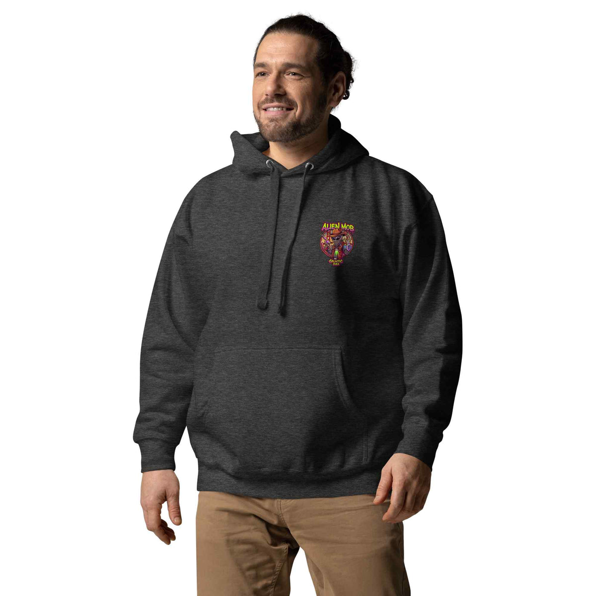 man wearing a charcoal color hoodie with a logo on the left side chest of a design alien mob cowboy outlaw paired with khaki jeans on a white background front view