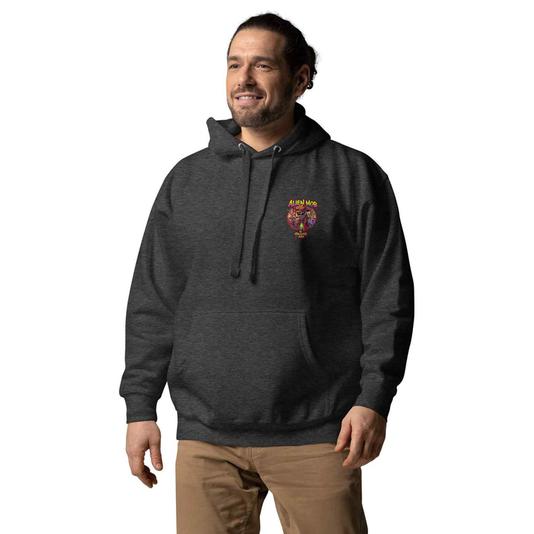 man wearing a charcoal color hoodie with a logo on the left side chest of a design alien mob cowboy outlaw paired with khaki jeans on a white background front view