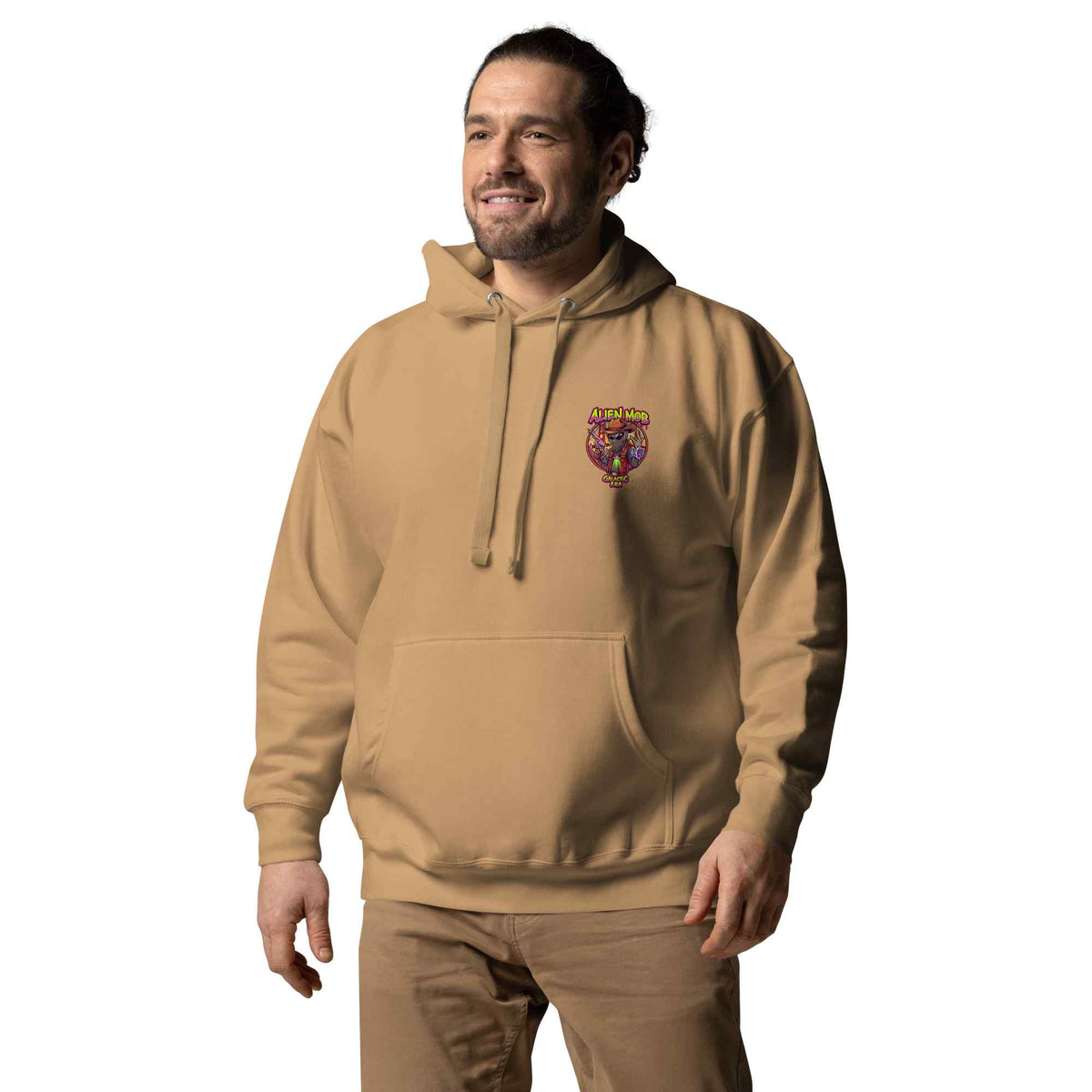 man wearing a khaki color hoodie with a logo on the left side chest of a design alien mob cowboy outlaw paired with khaki jeans on a white background front view