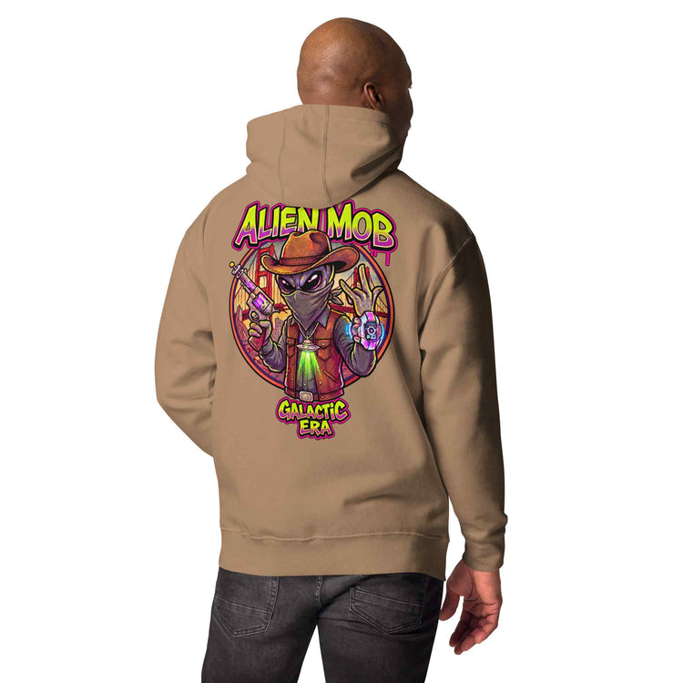 man wearing a latte hoodie with custom design alien mob cowboy outlaw print on the back of pullover hoodie paired with black jeans on a white background back view