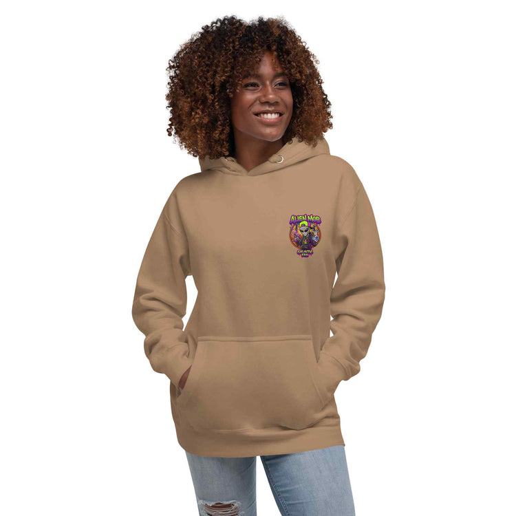 A woman with curly brown hair wearing a latte color  hoodie with a colorful alien mob graphic on the left chest, paired with light blue jeans, set against a plain white background.