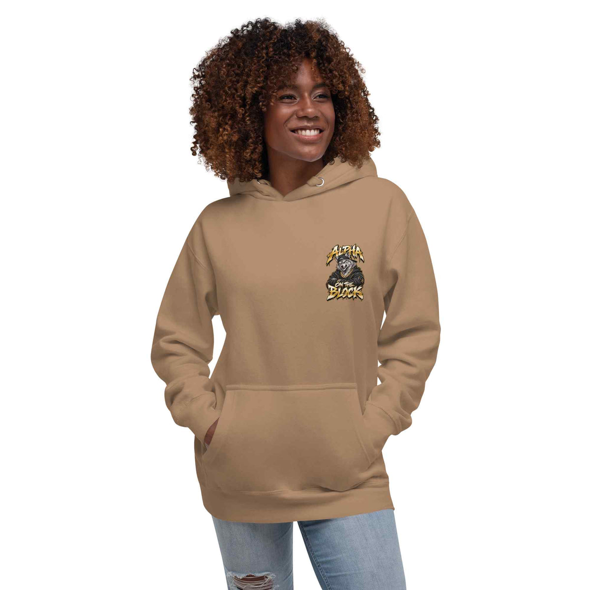 A woman with curly brown hair wearing a tan hoodie with a wolf logo graphic on the left chest, paired with light blue jeans, set against a plain white background.