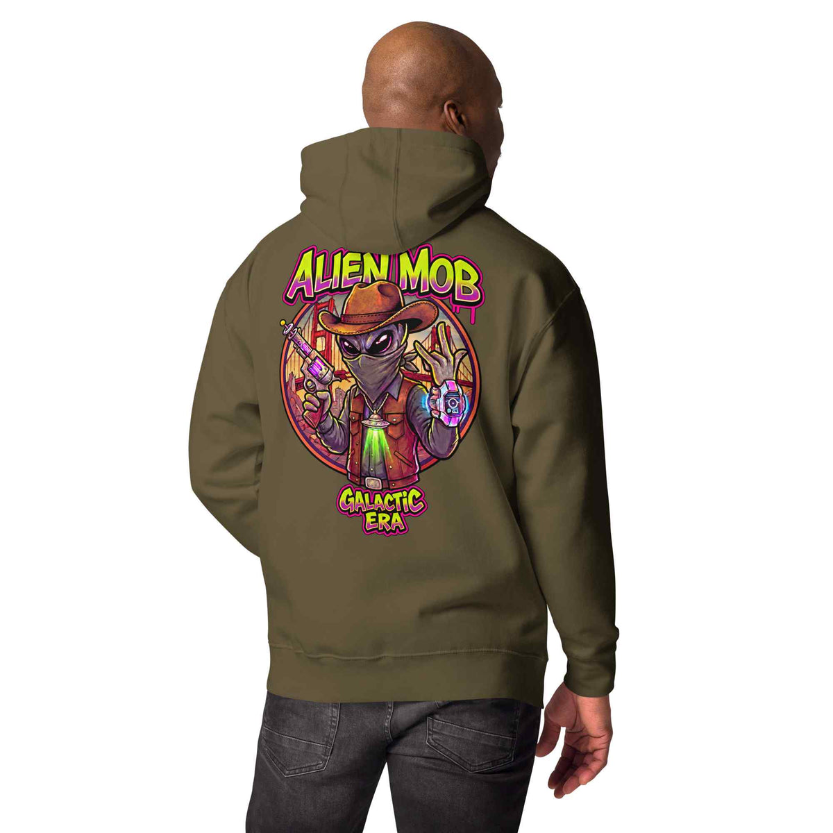 man wearing a military hoodie with custom design alien mob cowboy outlaw print on the back of pullover hoodie paired with black jeans on a white background back view