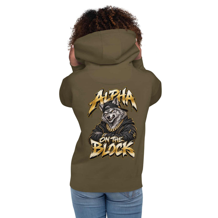 A woman shown from the back wearing an olive green hoodie with a large graphic print on the back featuring a wolf and the text 'ALPHA ON THE BLOCK' in gold and white. The child is also wearing blue jeans against a plain white background.
