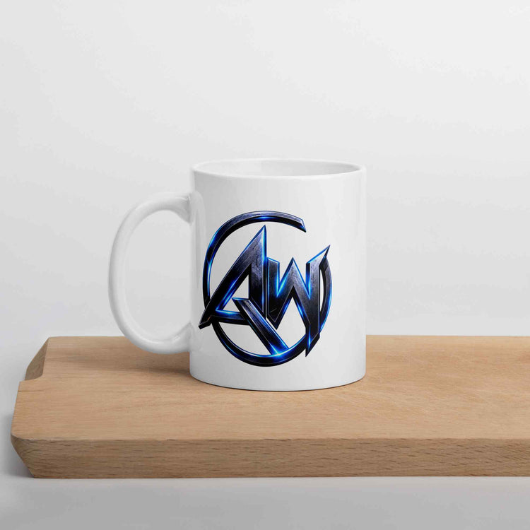 A white ceramic mug with a metallic blue and black circular 'AW' logo printed on the front, resting on a light wood tray against a plain white background.