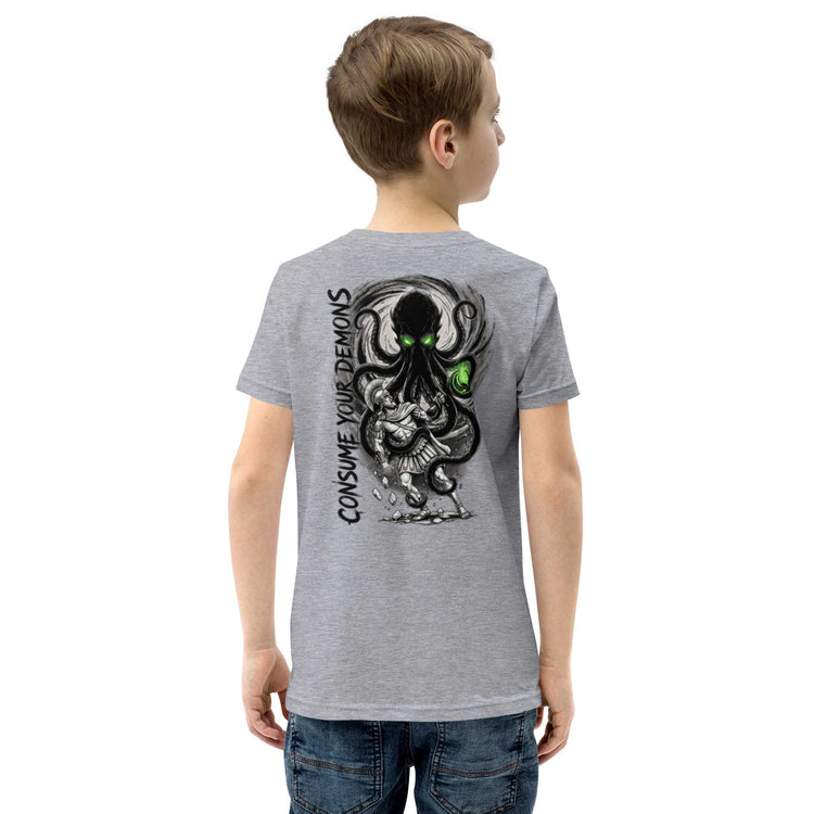 A child wearing a heather gray t-shirt, viewed from the back. The shirt features a large graphic print of a black octopus-like creature with glowing green eyes and the text 'CONSUME YOUR DEMONS' in black.