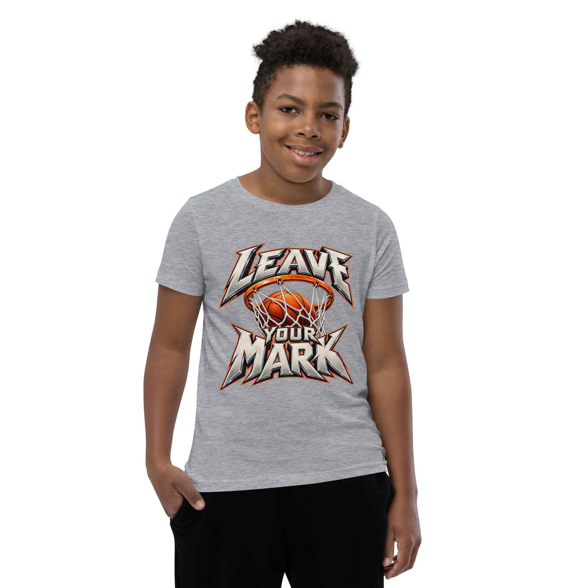 A young boy wearing a heather gray t-shirt with a basketball-themed graphic that reads 'LEAVE YOUR MARK' in orange, white, and black. He is standing against a solid white background.