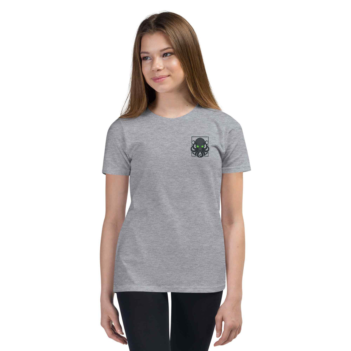 A young woman modeling a heather gray short-sleeve t-shirt with a small kraken creature graphic on the left chest, set against a plain white background.