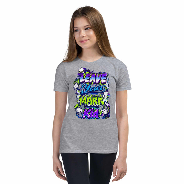 A young woman modeling a heather gray t-shirt with a colorful graphic that reads 'LEAVE YOUR MARK Kid' in stylized purple, green, and white lettering, set against a plain white background.
