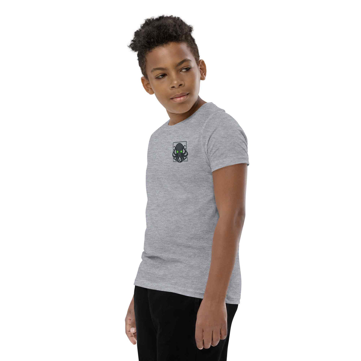 A child model wearing a heather gray short-sleeve t-shirt with a kraken graphic on the chest, paired with black pants, set against a plain white background.