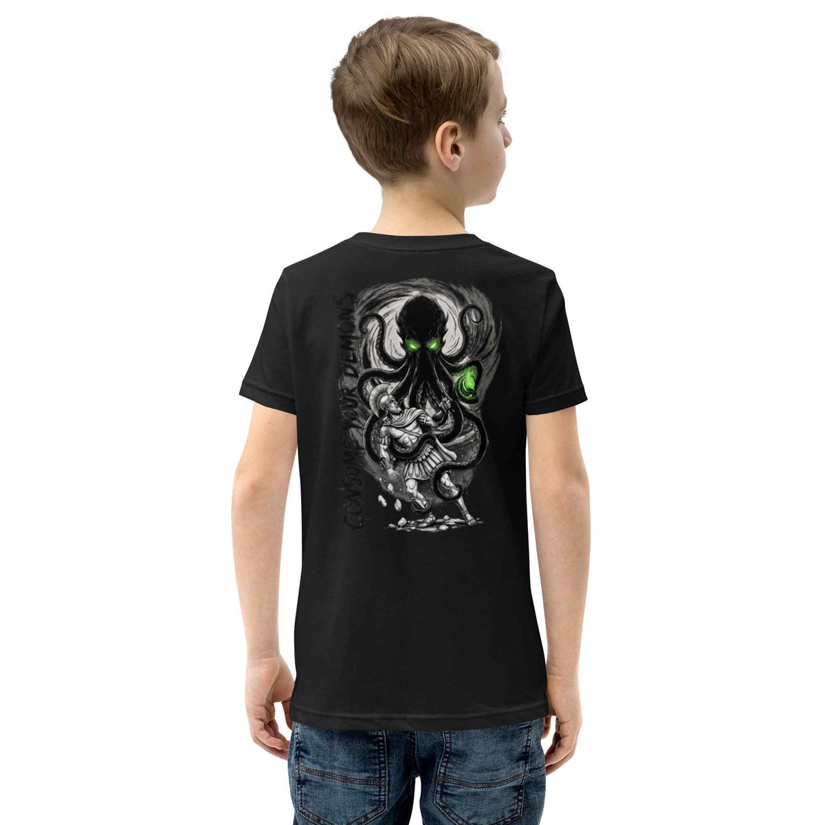 A child viewed from the back wearing a black short-sleeve T-shirt with a large kraken monster graphic and a bright green glowing eye on the back, paired with blue jeans against a plain white background.