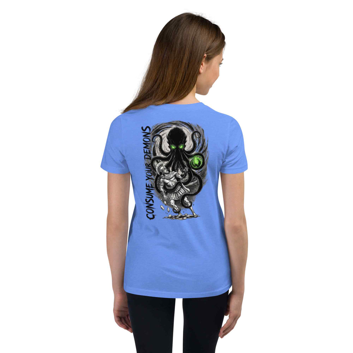 A woman viewed from the back wearing a light blue short-sleeve t-shirt with a large graphic print on the back. The graphic features a black and gray octopus-like creature with glowing green eyes and the text 'CONSUME YOUR DEMONS' printed vertically.