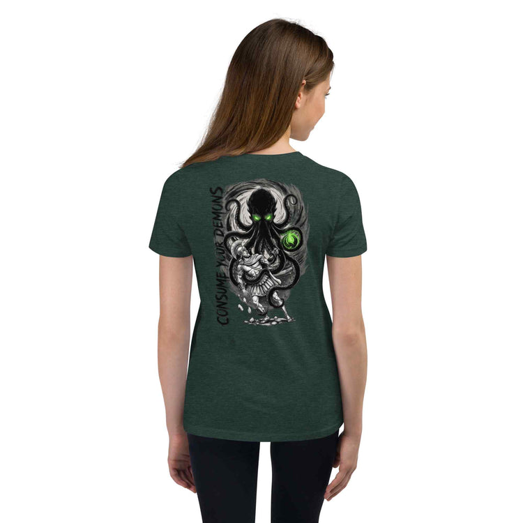 A woman shown from the back wearing a black short-sleeve T-shirt with a white text graphic kraken character, goal, obstacle, stakes, perspective, world, and twist, plus the phrase consume your demons