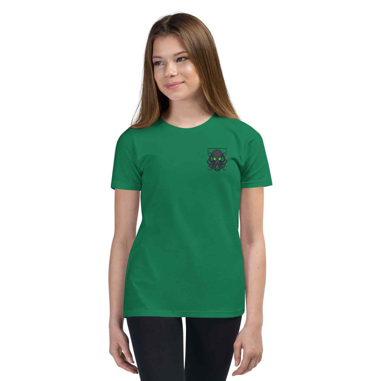 A young woman modeling a green short-sleeve crewneck t-shirt with a small black octopus graphic on the left chest, set against a plain white background.