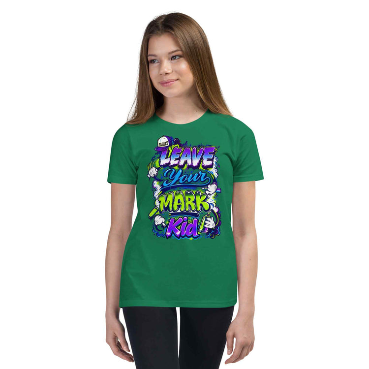 A young woman modeling a green short-sleeve t-shirt with a colorful graphic that reads 'LEAVE YOUR MARK Kid' in purple, yellow, and white stylized lettering, set against a plain white background.