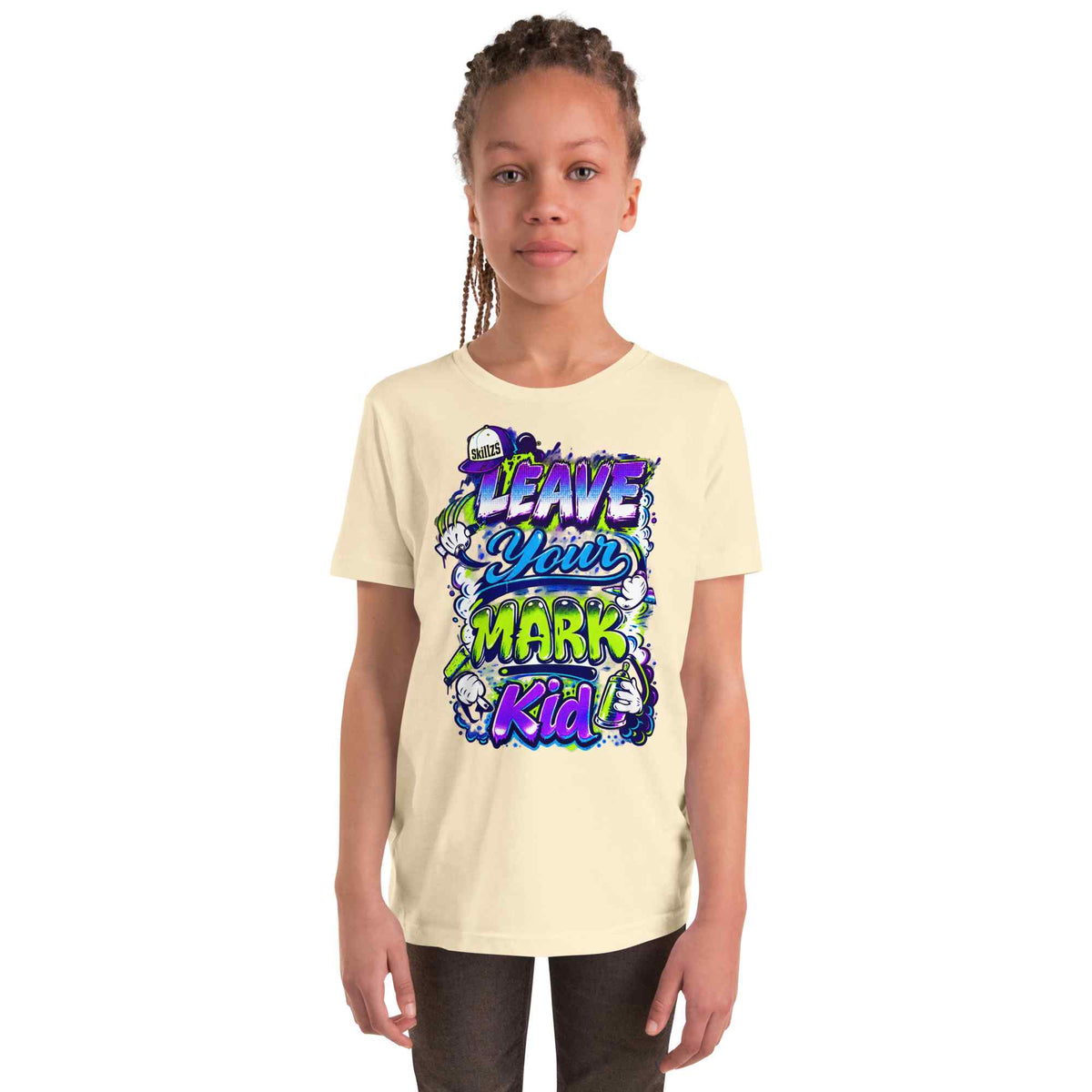 A child model wearing a cream-colored t-shirt with a colorful graphic print that reads 'LEAVE YOUR MARK Kid' in stylized purple, blue, and green lettering, set against a plain white background.