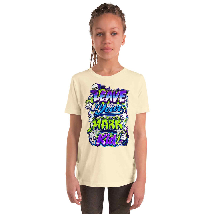 A child model wearing a cream-colored t-shirt with a colorful graphic print that reads 'LEAVE YOUR MARK Kid' in stylized purple, blue, and green lettering, set against a plain white background.