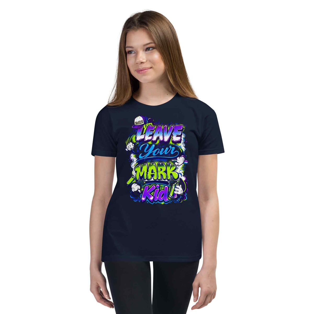 A young woman modeling a navy blue t-shirt with a colorful graphic that reads 'LEAVE YOUR MARK Kid' in purple, green, and white text with cartoon characters.